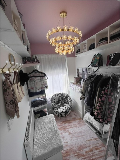 Dressing room after: a boutique walk-in wardrobe with a soft pink ceiling, statement chandelier, open rails and styled storage