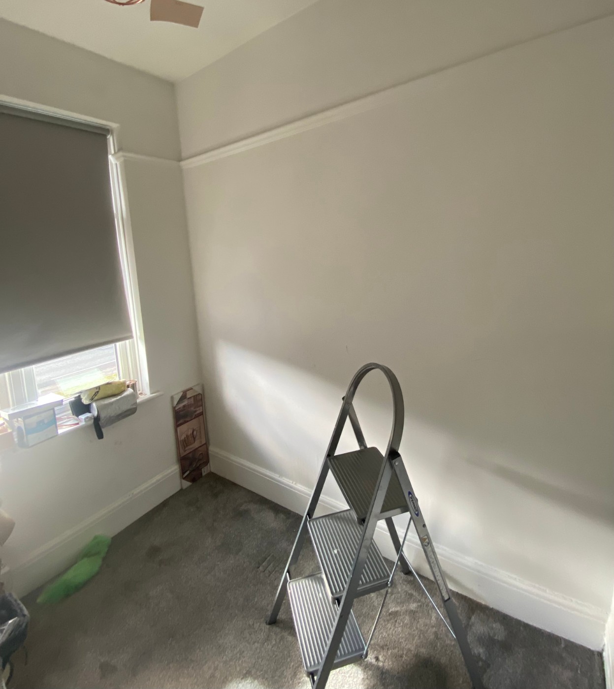 Dressing room before: an empty box room with grey carpet, bare walls and a step ladder