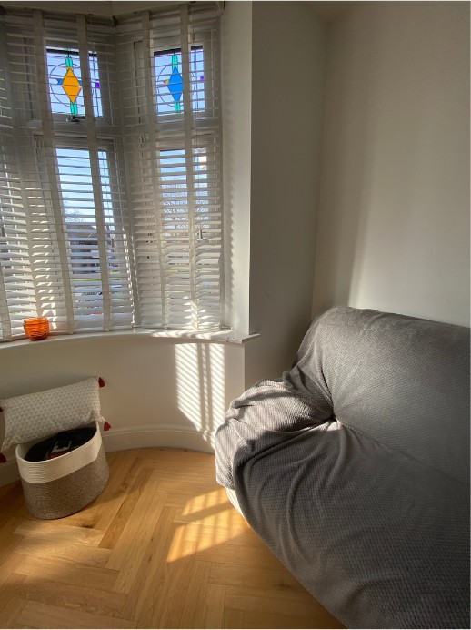 Living room before: a plain bay-window corner with a grey sofa and bare walls